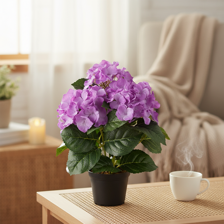 Lilla hortensiablomst i beige potte plassert i en vinduskarm i en lun stue med utsikt mot grønne trær og natur.