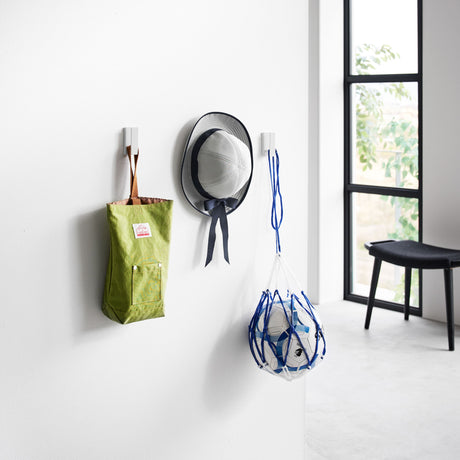 Kroker i hvit metall brukt som oppheng for gardiner i stue.