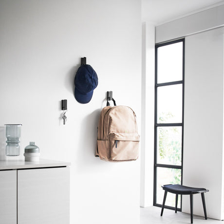 3pk sorte kroker i metall festet på rekke i gang med klær hengende.