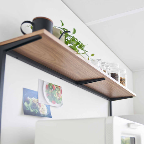 Underside av kjøkkenhylle med treplate og stålramme montert på kjøkkenbenk