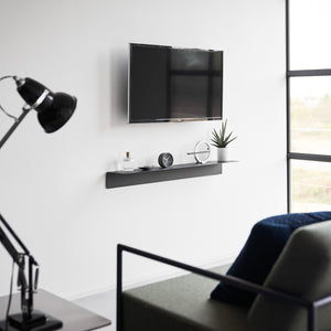 Svevende sorte skuffehyller i moderne stue med TV