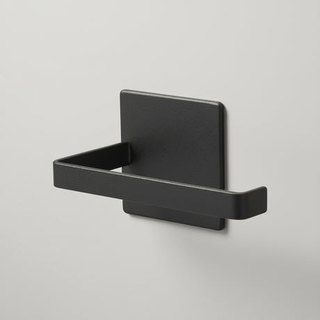 Sort magnetisk dorullholder montert på vaskemaskin på badet.