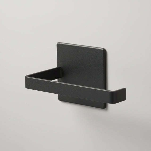 Sort magnetisk dorullholder montert på vaskemaskin på badet.