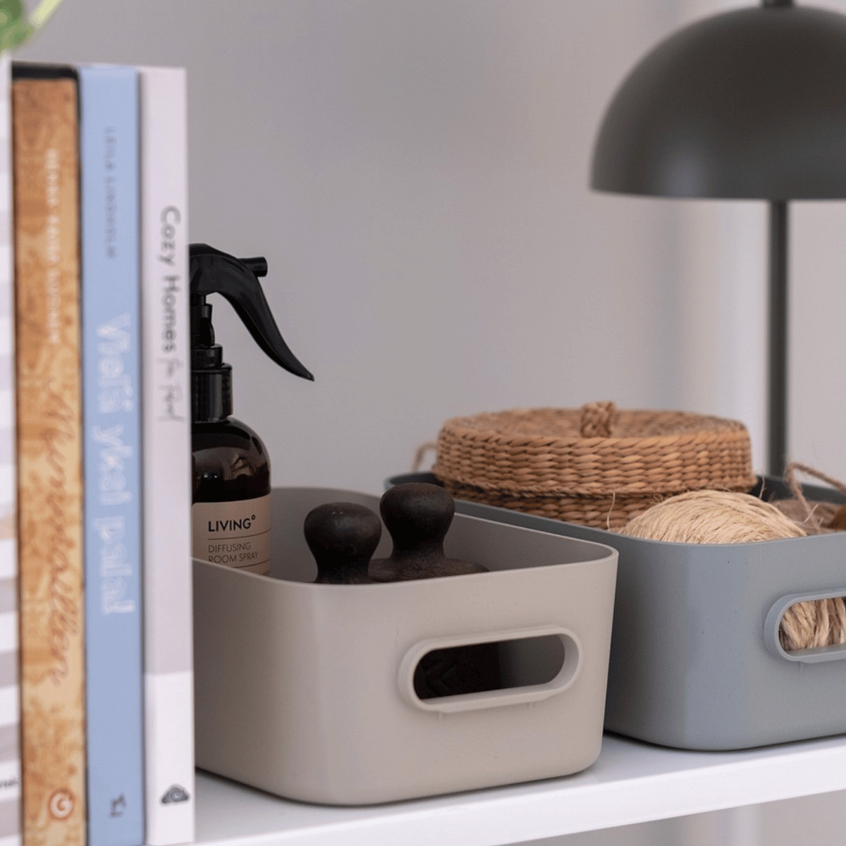 Beige og grå SmartStore Comfort oppbevaringskurver ved siden av bøker på hylle i stuen