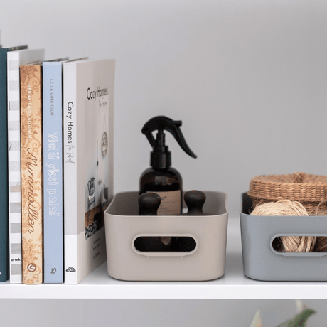 Beige og grå SmartStore Comfort oppbevaringskurver på stuehylle med romspray, bøker og pynt