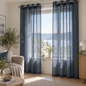 Marineblå transparente gardiner med maljer i lys nordisk stue med beige sofa, treverk og naturlig dagslys.
