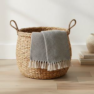 Kvadratisk produktbilde av grått bomullspledd med lyse frynser