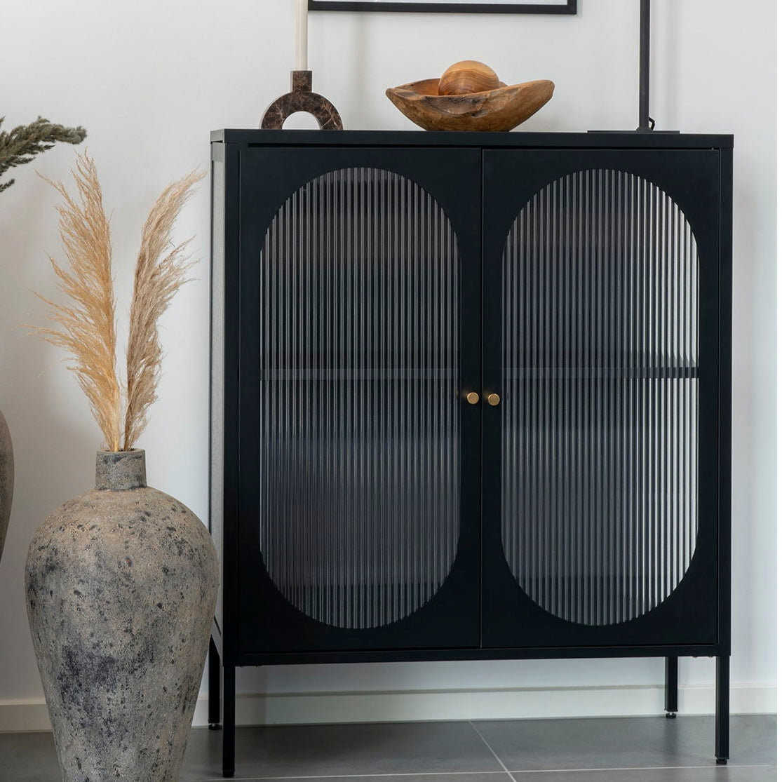 Svart oppbevaringsskap med riflede glassdører og messinghåndtak.