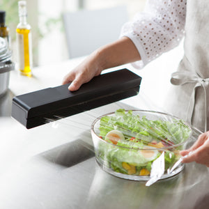 Person river av plastfolie fra sort magnetisk holder.