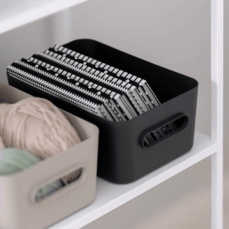 Koksgrå SmartStore Comfort-förvaringskorg med stickor bredvid en beige korg med garn