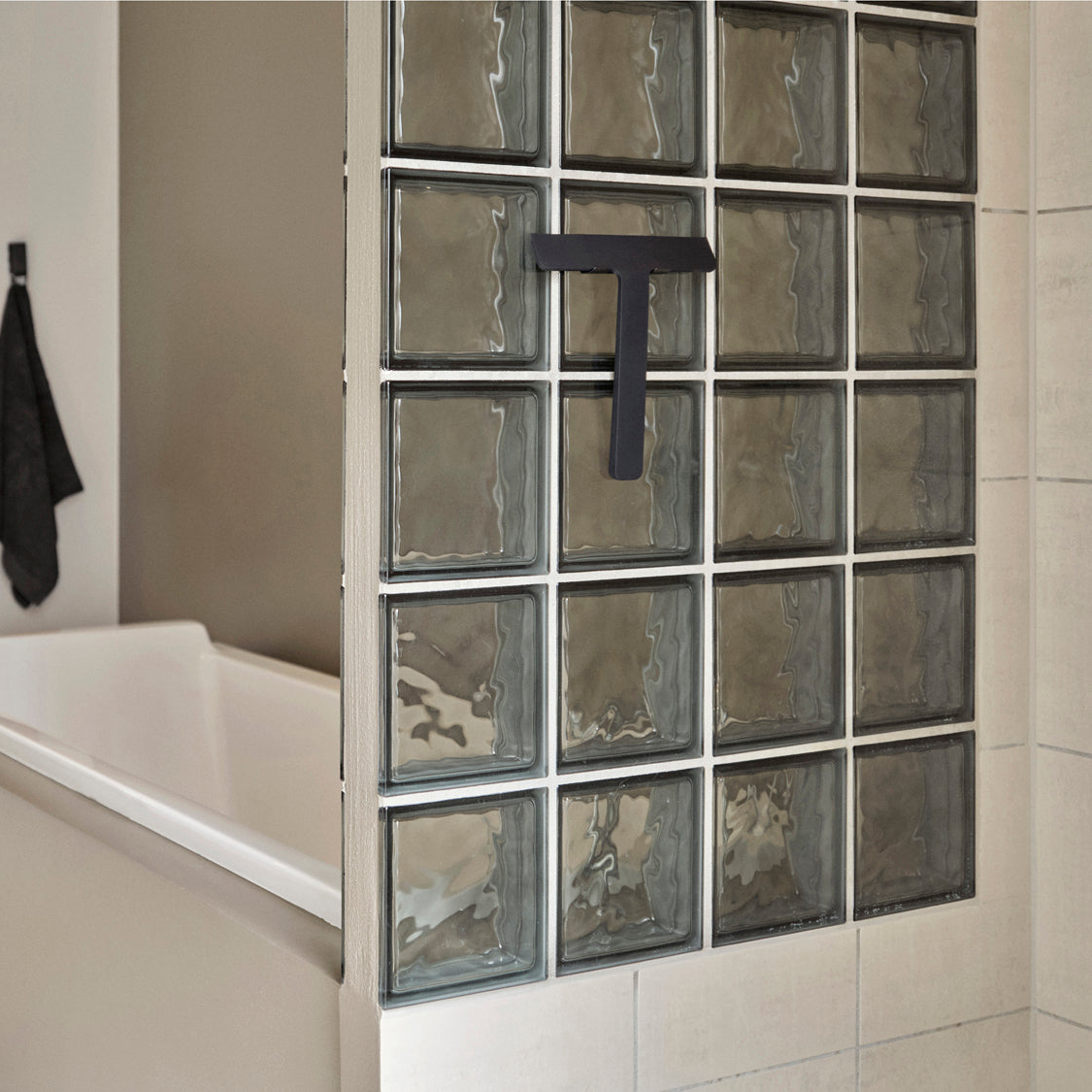 Ume dusjskrape i sort montert på vegg ved dusj