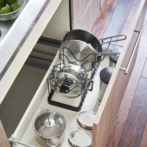 Sort panneholder for praktisk oppbevaring av gryter og lokk.