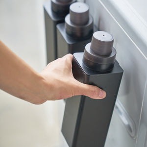 Sort magnetisk flaske for oppvaskmiddel festet på vaskemaskin.