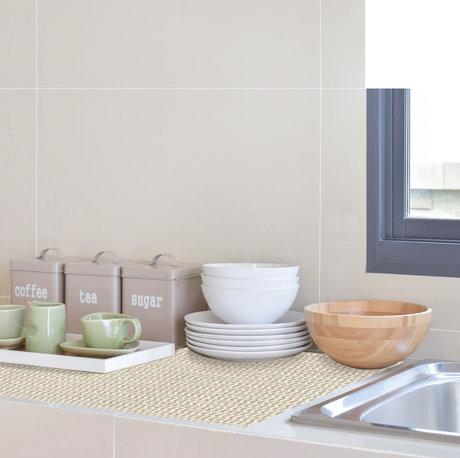 Beige hyllematte under servise på kjøkkenbenk som beskytter overflater og demper støy.