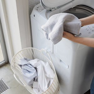 Vaskerom med hvit magnetisk krok og skittentøyskurv hengende.