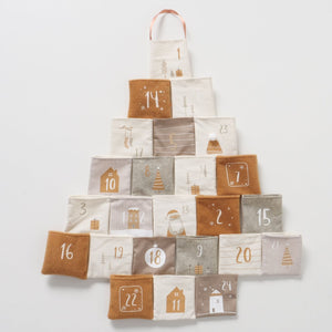 Adventskalender i stoff formet som juletre med 24 nummererte lommer i krem, grå og brun.