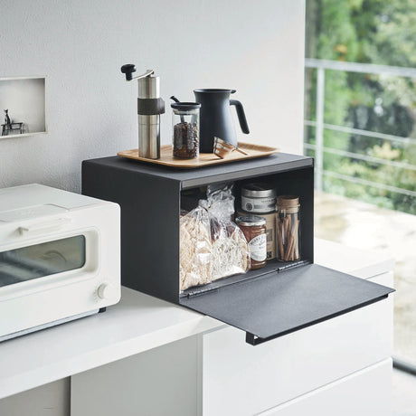 Sort brødboks i stål med magnetisk lokk plassert på kjøkkenbenk