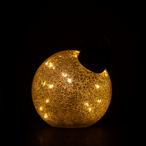 Miljøbilde av liten LED julekule i gull på bord.