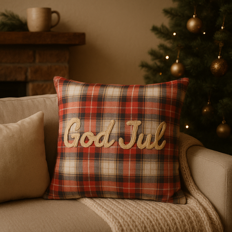 "Putetrekk i rødt rutemønster med teksten God Jul, plassert i beige sofa med juletre i bakgrunnen – klassisk julepynt til stue.