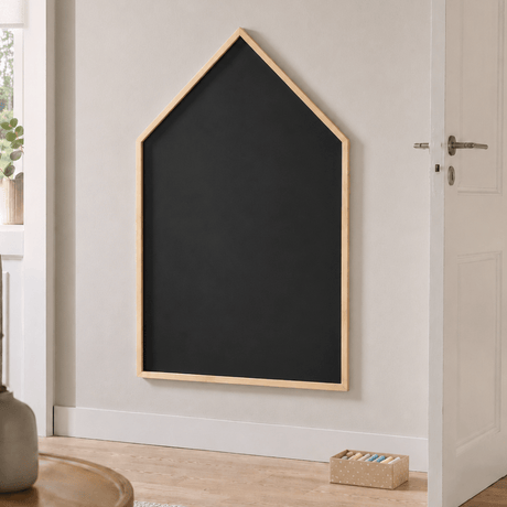 Husformet svart krittavle montert på vegg i lyst nordisk interiør med enkel og rolig styling.