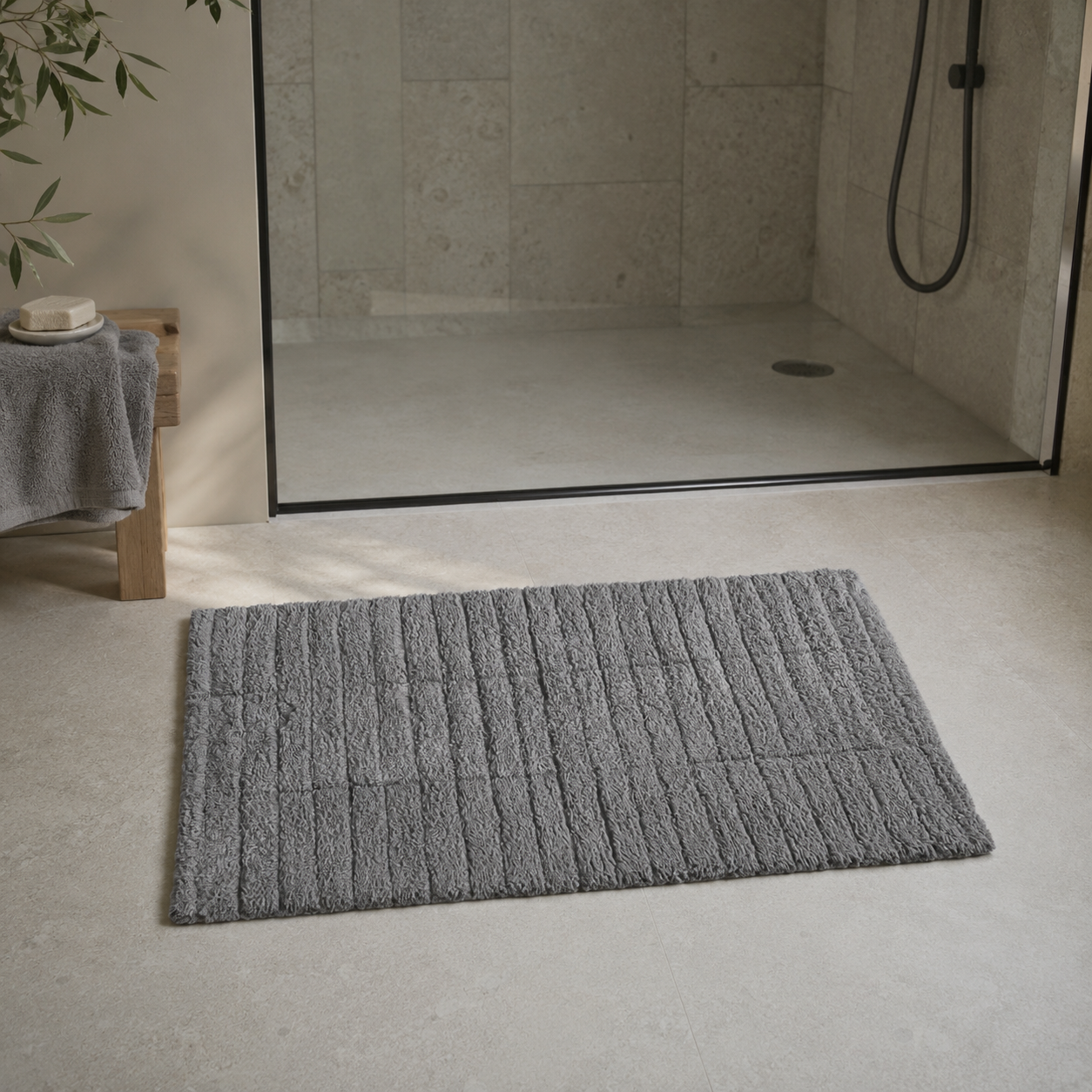 Grå Tiles baderomsmatte foran en dusj med glassvegg i et moderne baderom. - Lindas dekor