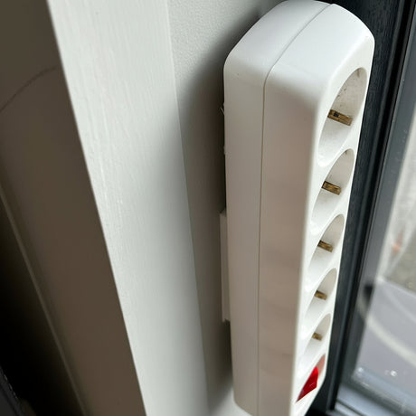 Praktisk hvit holder for grenuttak brukt til skjult ledningsføring