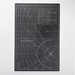 Svart skjærematte med hvite linjer og mønster for presise kutt, ideell for hobby og håndverk.