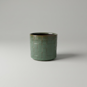 Firkantet grønn blomsterpotte i keramikk på hylle med planter, skandinavisk interiør