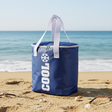 Blå kjølebag med hvite håndtak og glidelås sett fra siden, perfekt til strandtur.