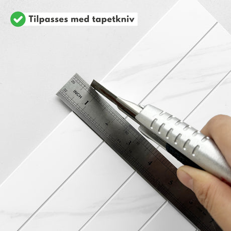 Installasjonsbilde: hender som monterer Alma hvit marmorfliser på vegg.