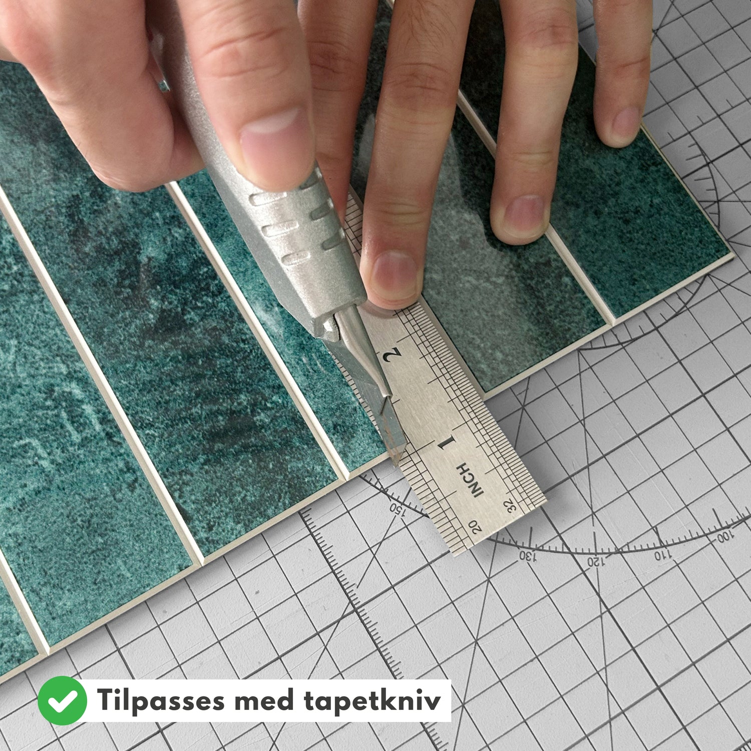 Hender som kutter Alma grønn marmorfliser til riktig størrelse med tapetkniv.