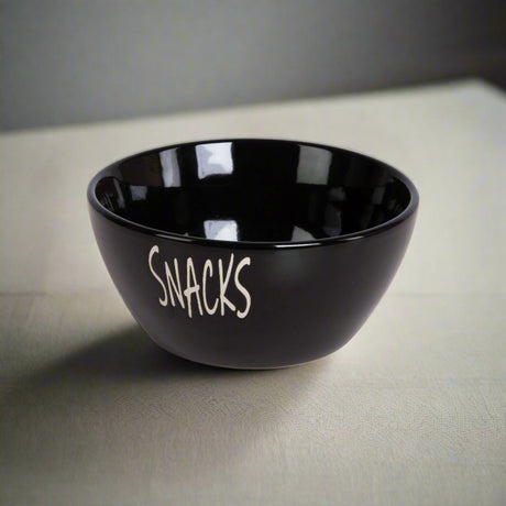 Keramisk snacks-skål i sort på lys bordflate, med myk belysning og skygge.