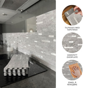 Selvklebende EasyTiles Pro fliser montert som backsplash på kjøkkenvegg, grå stein-look, med stabel av fliser foran. Viser at flisene kan tilpasses med tapetkniv, er vanntette og enkle å rengjøre.