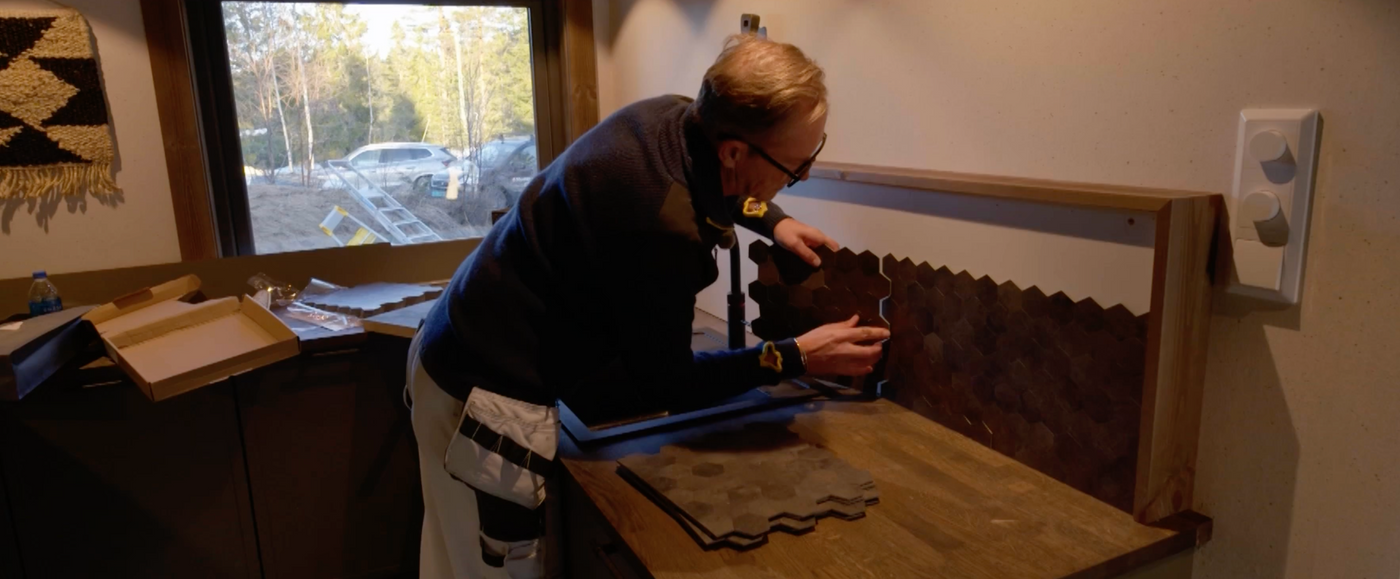 Halvor Bakke monterer Hexagon mørk betong selvklebende fliser fra Lindas Dekor på kjøkkenet i Setesdal-hytta under innspillingen av Eventyrlig Oppussing.