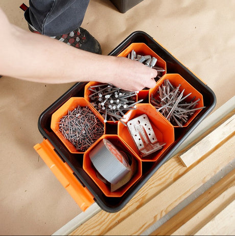 Person organiserer skruer og spiker i oppbevaringsboks med innsats