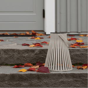 Beige solarlykt plassert på en steintrapp ved et inngangsparti med høstløv rundt. - Lindas dekor