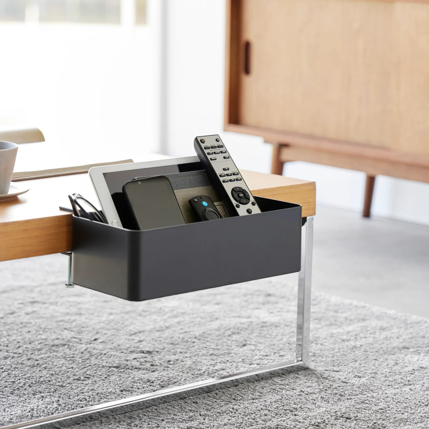 Svart bordmontert kurv til fjernkontroller, notatbøker og kabler