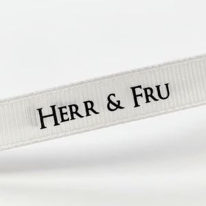 Nærbilde av hvitt gavebånd med sort «Herr & Fru»-tekst som viser tekst, struktur og bredde tydelig. - Lindas dekor 