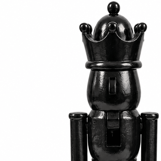 Nærbilde av svart nøtteknekkerfigur med blank overflate, dekorativ krone og detaljer i ansikt og uniform.