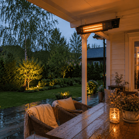 Veggmontert terrassevarmer lyser over en lun norsk veranda med vått tregulv og grønn hage i skumringen.