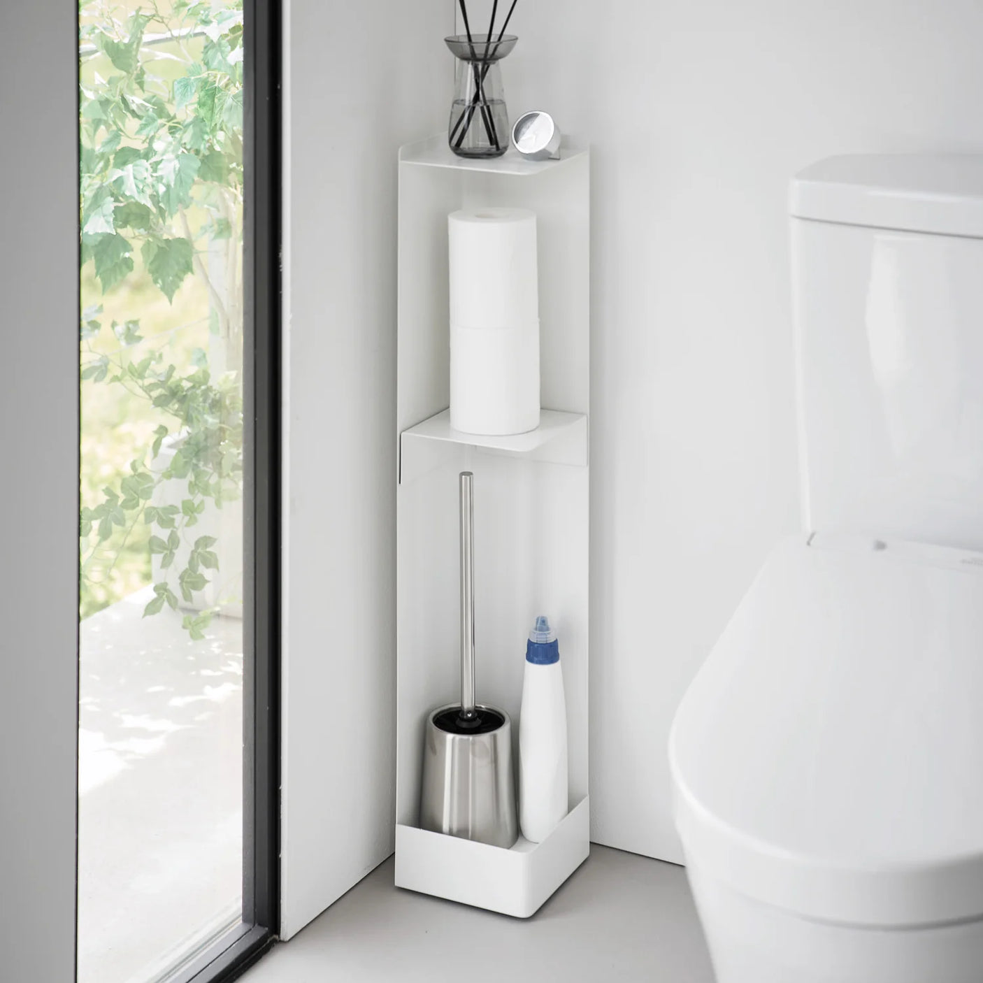 Hvit holder til toalettruller og rengjøringsartikler ved toalett