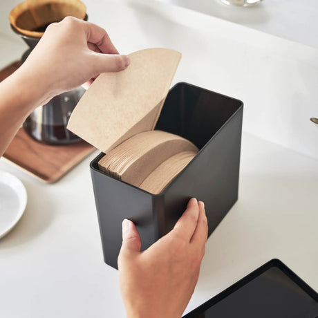 Sort filterboks til kaffefilter med lokk plassert på kjøkkenbenk