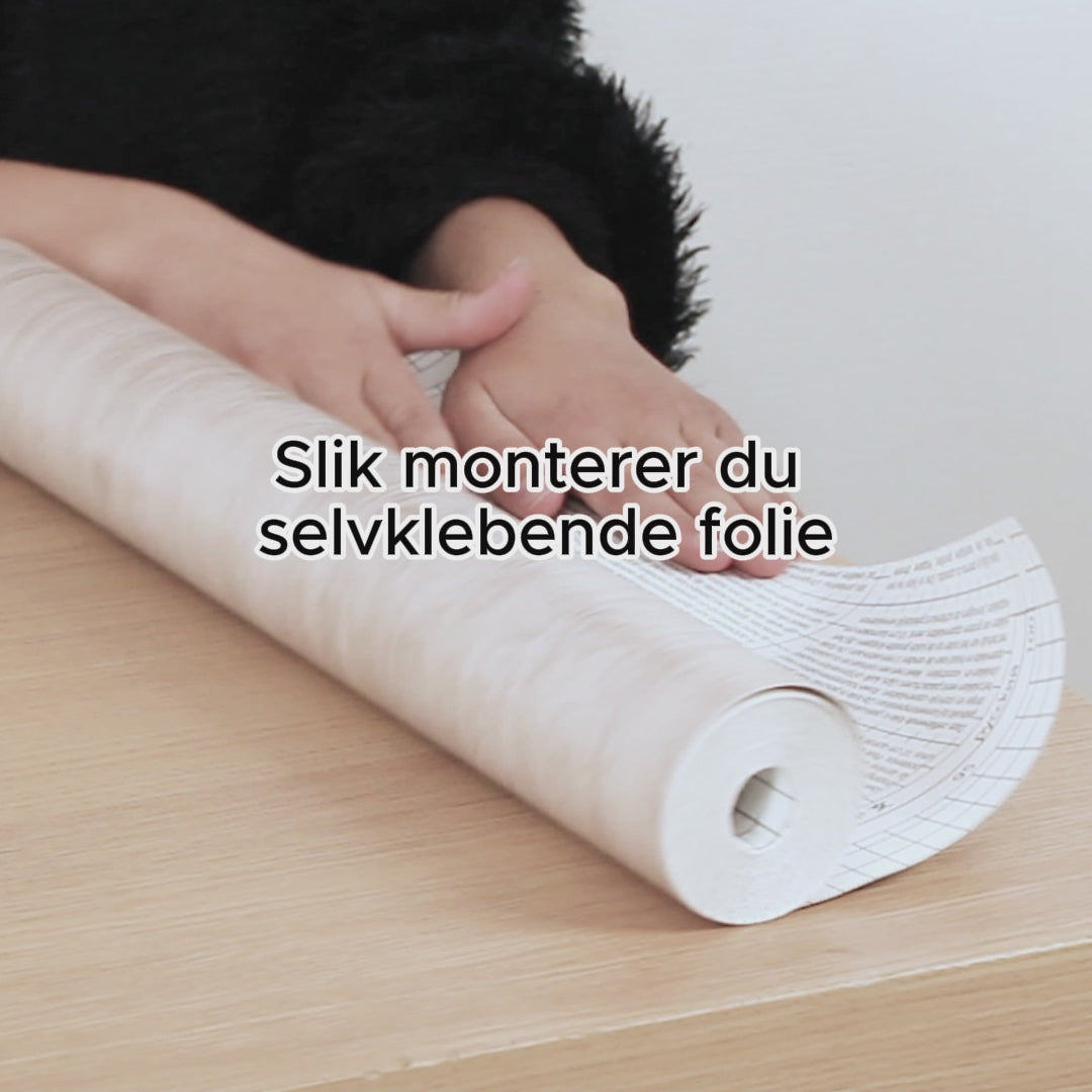 Transparent glossy kontaktplast rulles ut på bordflate