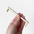 Hånd holdt håndtak i børstet messing med moderne, minimalistisk design.